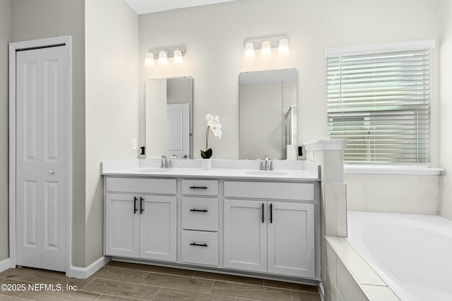 bathroom featuring vanity and tiled tub