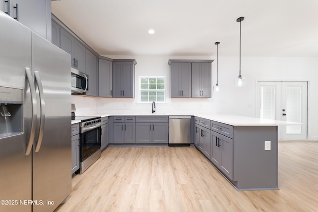 kitchen with hanging light fixtures, appliances with stainless steel finishes, sink, and gray cabinetry