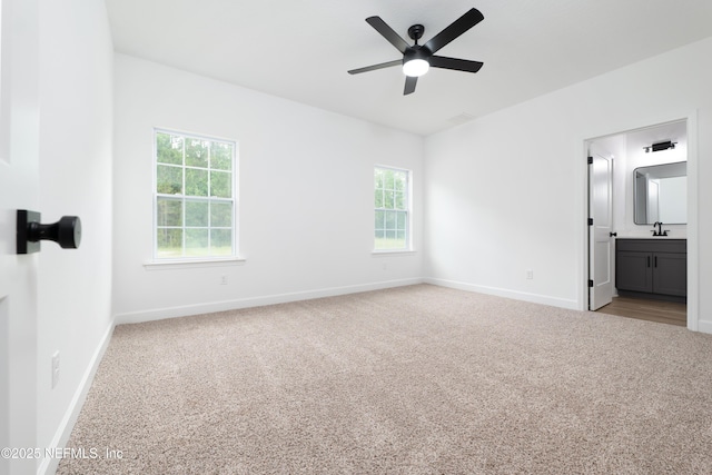 unfurnished bedroom with light carpet, connected bathroom, and multiple windows