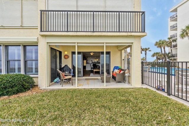 back of house with a balcony, a yard, and a patio area