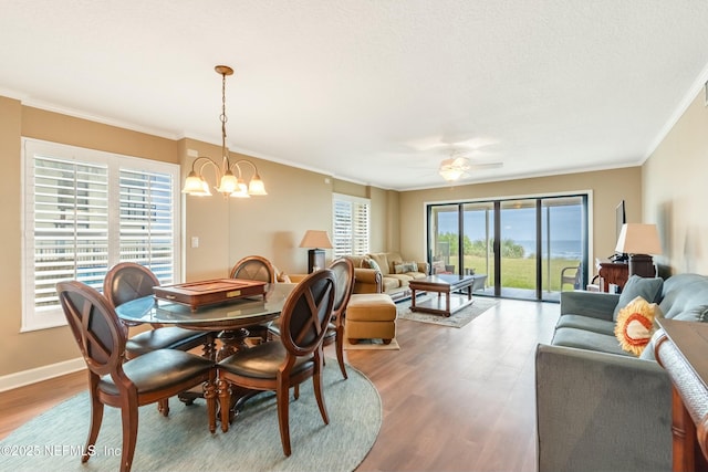 dining room with crown molding, ceiling fan with notable chandelier, and hardwood / wood-style floors