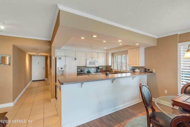 kitchen featuring sink, white appliances, ornamental molding, white cabinets, and kitchen peninsula