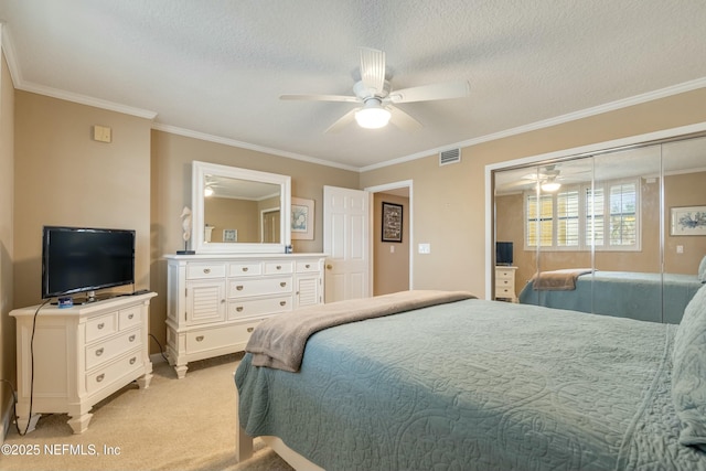 carpeted bedroom featuring ceiling fan, ornamental molding, a closet, and a textured ceiling