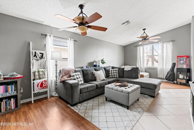 living room with ceiling fan, vaulted ceiling, a textured ceiling, and a wealth of natural light