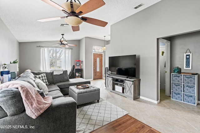 living room with lofted ceiling, ceiling fan, a textured ceiling, and light tile patterned flooring