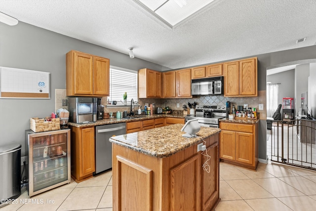 kitchen with wine cooler, stainless steel appliances, light tile patterned flooring, and sink