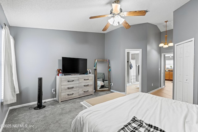 carpeted bedroom featuring vaulted ceiling, ceiling fan with notable chandelier, a textured ceiling, and a closet