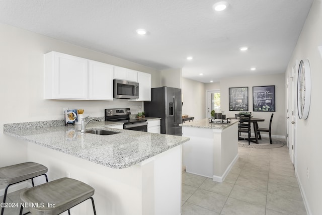 kitchen featuring sink, a breakfast bar, stainless steel appliances, a center island, and kitchen peninsula