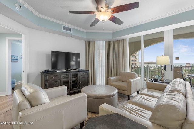 living room with crown molding, ceiling fan, and light wood-type flooring