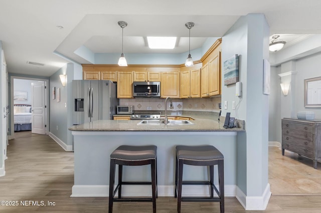 kitchen with sink, tasteful backsplash, light brown cabinets, appliances with stainless steel finishes, and kitchen peninsula