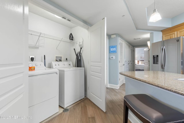 laundry room with separate washer and dryer and light hardwood / wood-style flooring