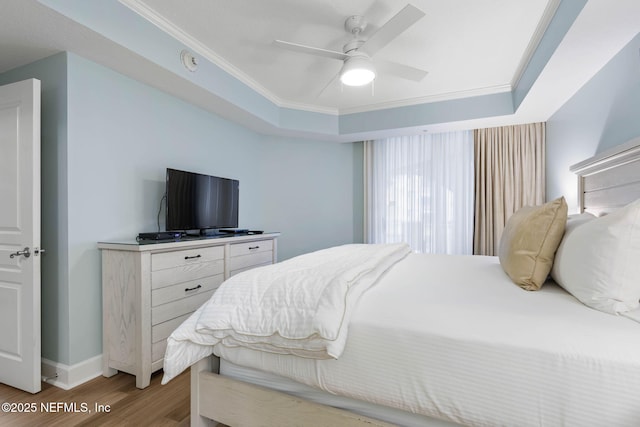 bedroom featuring crown molding, a tray ceiling, wood-type flooring, and ceiling fan