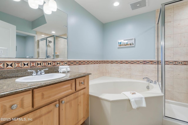 bathroom with vanity, separate shower and tub, and tile walls