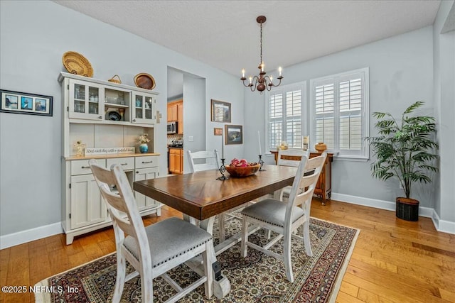 dining space with a chandelier, light hardwood / wood-style flooring, and a textured ceiling