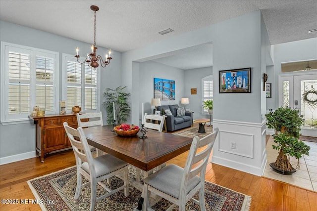 dining area with hardwood / wood-style flooring, a textured ceiling, and a notable chandelier