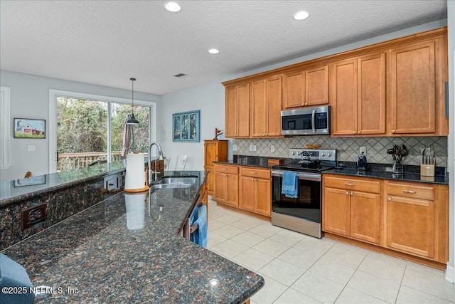 kitchen featuring sink, appliances with stainless steel finishes, dark stone countertops, backsplash, and hanging light fixtures