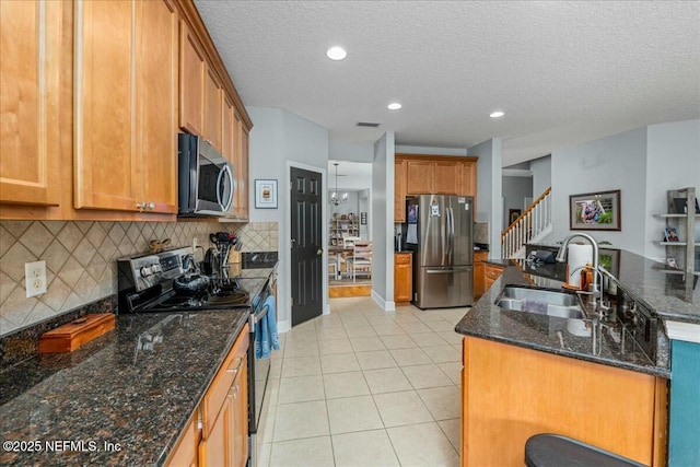 kitchen featuring tasteful backsplash, sink, dark stone countertops, light tile patterned floors, and stainless steel appliances