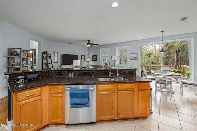 kitchen with pendant lighting, sink, dishwasher, a center island with sink, and dark stone counters