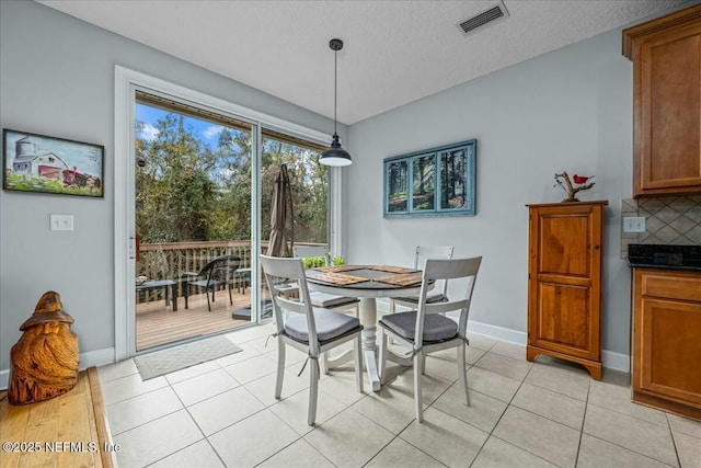 dining space with a textured ceiling and light tile patterned floors