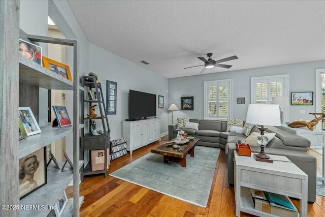 living room with ceiling fan, light hardwood / wood-style flooring, and a textured ceiling