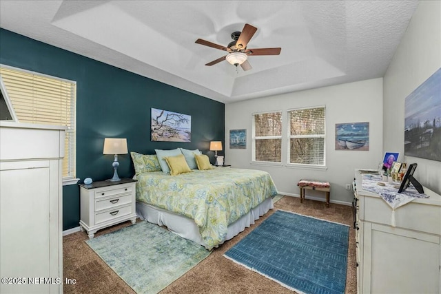 carpeted bedroom featuring a raised ceiling, ceiling fan, and a textured ceiling