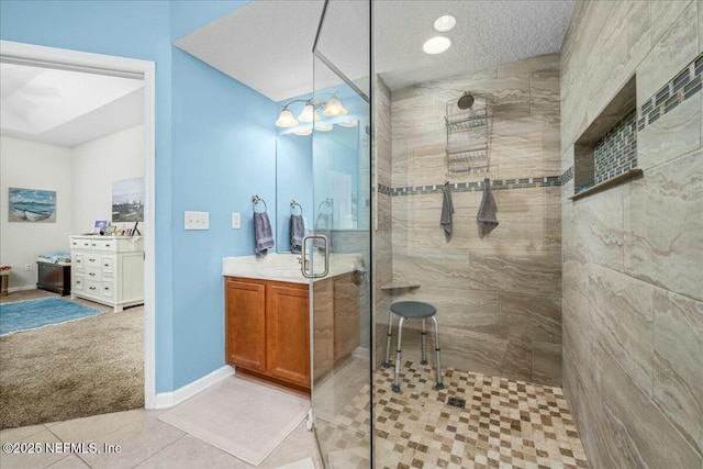 bathroom with tiled shower, vanity, tile patterned floors, and a textured ceiling