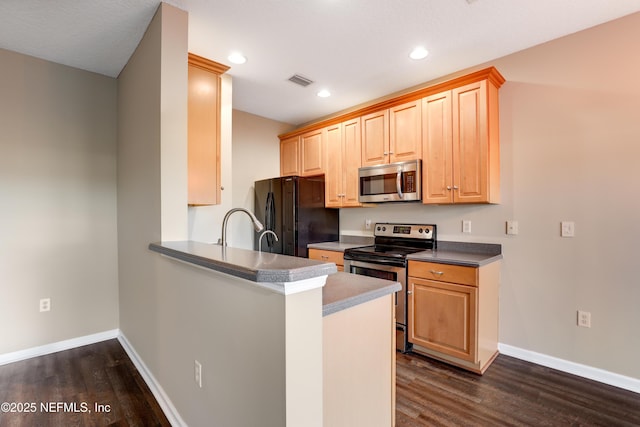 kitchen featuring stainless steel appliances, dark wood-type flooring, light brown cabinets, and kitchen peninsula