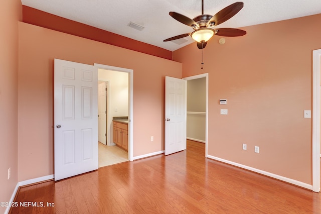 unfurnished bedroom featuring connected bathroom, light hardwood / wood-style flooring, and ceiling fan