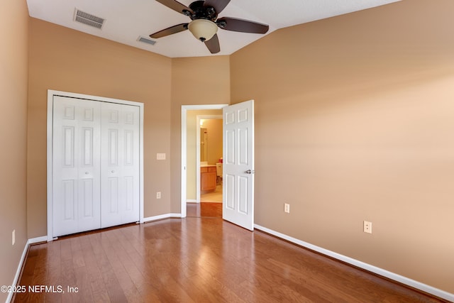 unfurnished bedroom with lofted ceiling, hardwood / wood-style floors, a closet, and ceiling fan