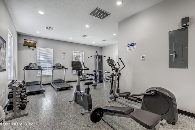 gym with electric panel and a textured ceiling