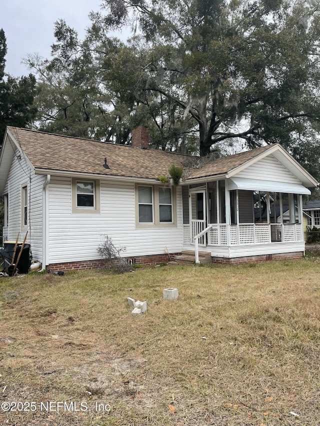 ranch-style home with a sunroom, covered porch, and a front lawn