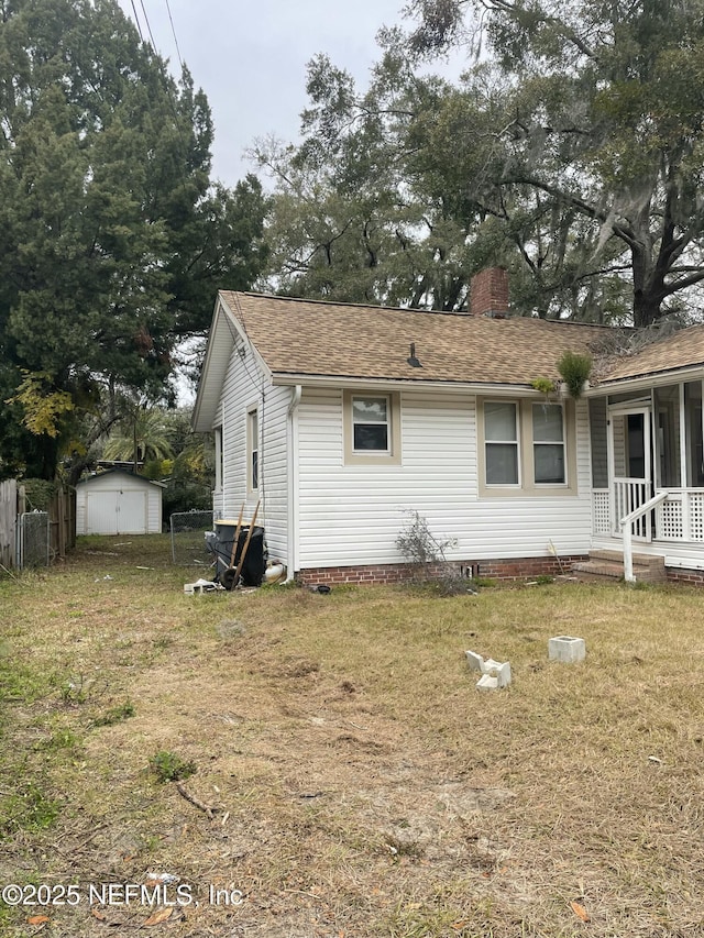 view of side of home featuring a lawn and a storage unit