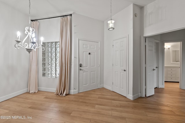 entryway with high vaulted ceiling, light hardwood / wood-style flooring, and a notable chandelier