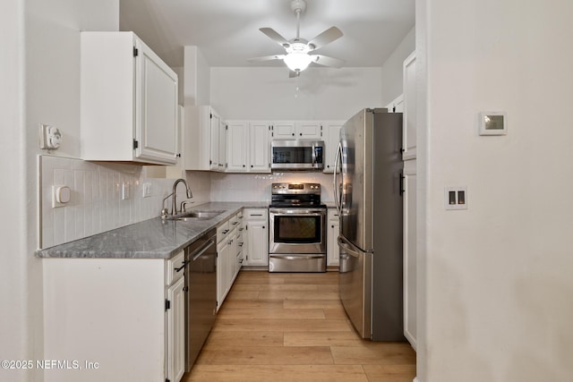 kitchen featuring sink, white cabinetry, stainless steel appliances, light hardwood / wood-style floors, and decorative backsplash