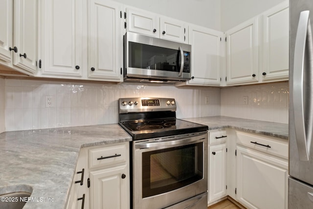 kitchen featuring white cabinetry, appliances with stainless steel finishes, light stone counters, and decorative backsplash