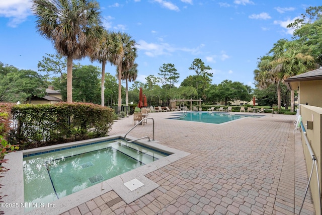 view of swimming pool featuring a hot tub and a patio