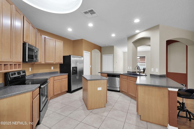 kitchen with sink, appliances with stainless steel finishes, a kitchen breakfast bar, a kitchen island, and kitchen peninsula