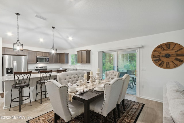 dining area featuring vaulted ceiling and light hardwood / wood-style floors