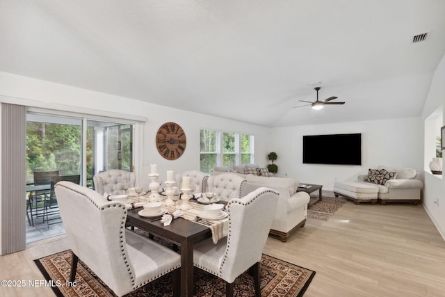 dining room with ceiling fan, vaulted ceiling, and light wood-type flooring