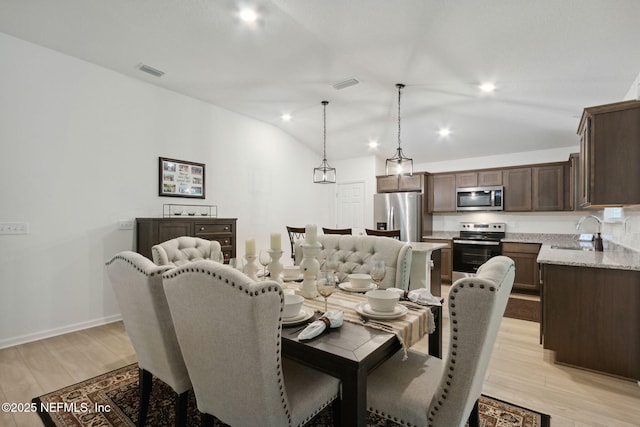 dining area with vaulted ceiling, sink, and light wood-type flooring