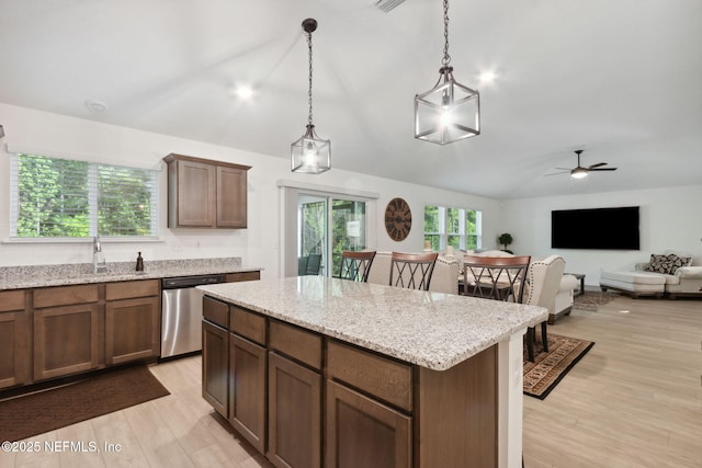 kitchen with pendant lighting, stainless steel dishwasher, light stone counters, and a kitchen island