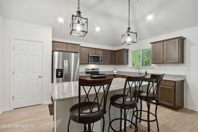 kitchen featuring light stone countertops, a kitchen bar, stainless steel appliances, and a kitchen island