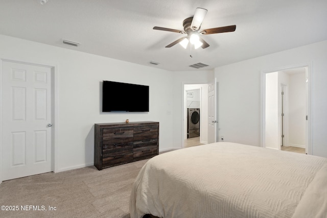 bedroom featuring ceiling fan, washer / clothes dryer, light colored carpet, and a spacious closet