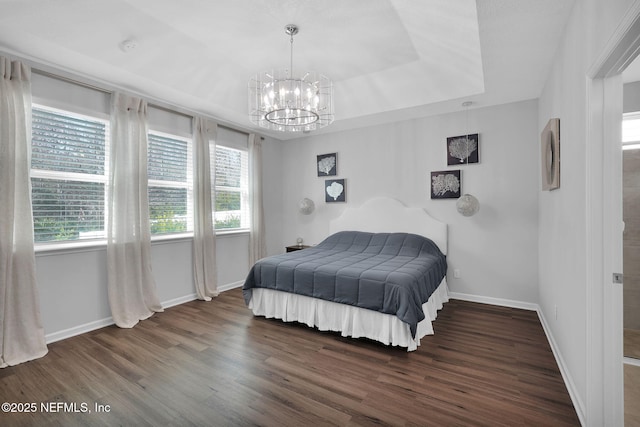 bedroom with a chandelier, dark hardwood / wood-style flooring, and a tray ceiling