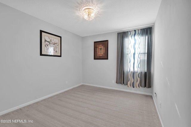 carpeted empty room featuring an inviting chandelier