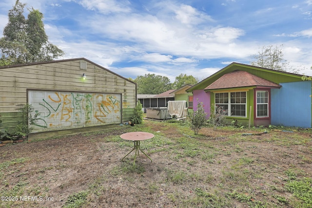 view of yard featuring a garage, a sunroom, and an outbuilding