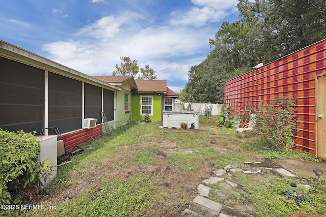 view of yard with a hot tub and a sunroom