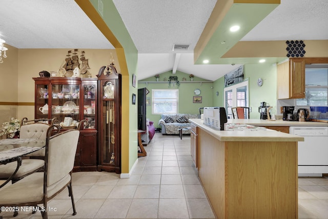 kitchen featuring lofted ceiling, light tile patterned floors, a textured ceiling, and white dishwasher