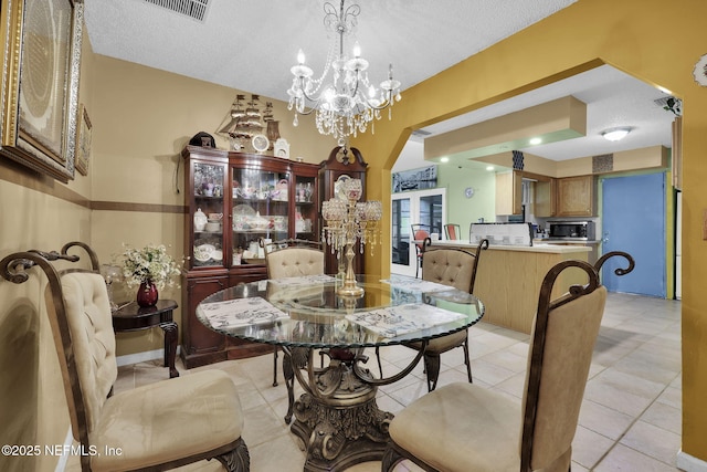 tiled dining space with a notable chandelier and a textured ceiling