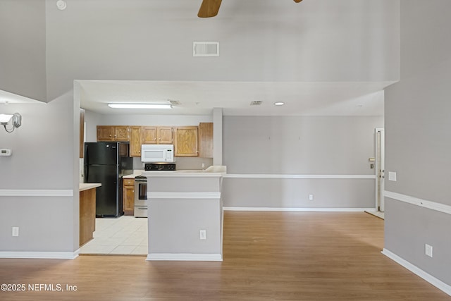 kitchen with light hardwood / wood-style floors, black fridge, ceiling fan, and stainless steel range with electric stovetop